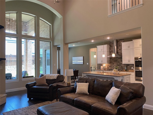 living room featuring dark wood-style floors, baseboards, and a towering ceiling