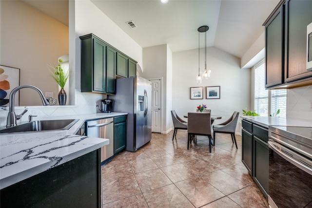 kitchen featuring green cabinetry, a sink, vaulted ceiling, appliances with stainless steel finishes, and pendant lighting