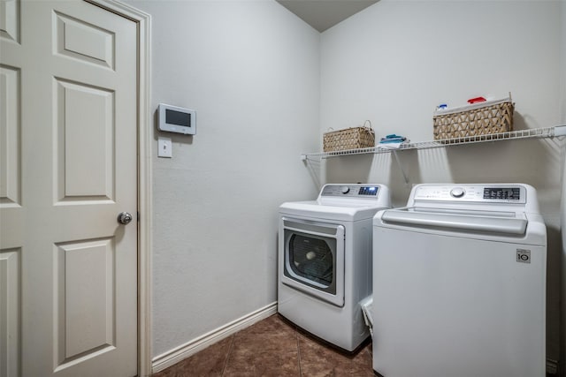 washroom featuring baseboards, separate washer and dryer, dark tile patterned floors, and laundry area