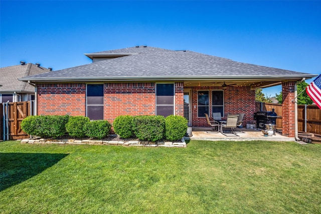 back of property with brick siding, a lawn, and fence