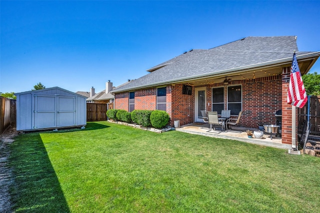 rear view of house featuring a shed, a yard, a fenced backyard, an outdoor structure, and brick siding