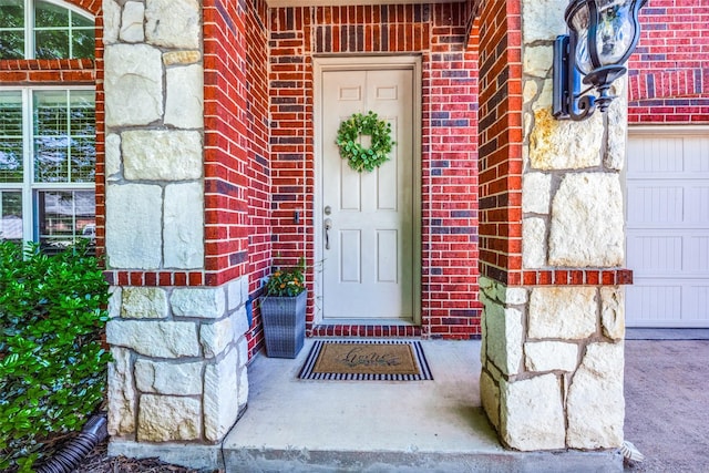 view of exterior entry with a garage, brick siding, and stone siding