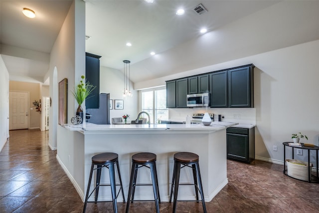 kitchen with visible vents, stainless steel appliances, a peninsula, a breakfast bar area, and light countertops