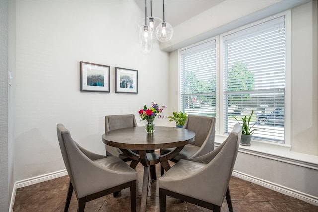 dining space with baseboards and dark tile patterned floors