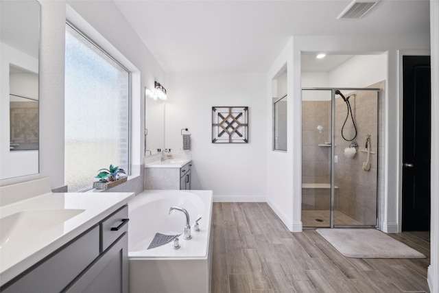 full bathroom with wood finished floors, visible vents, two vanities, a shower stall, and a bath