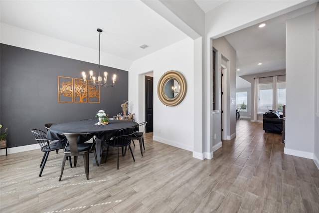 dining room with visible vents, wood finished floors, baseboards, and a chandelier