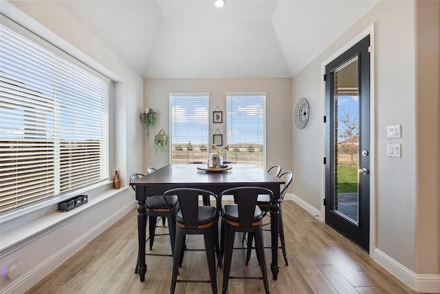 dining area with light wood-style flooring, baseboards, and vaulted ceiling