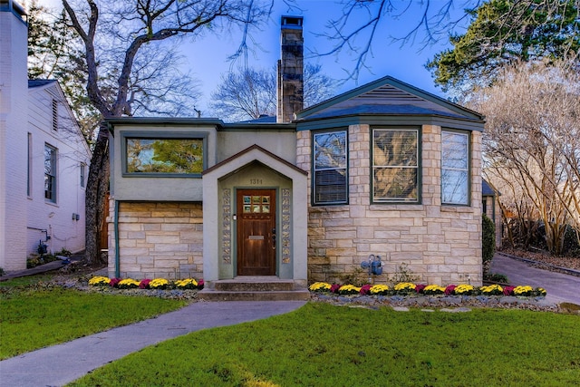 view of front facade featuring stone siding, a chimney, and a front yard