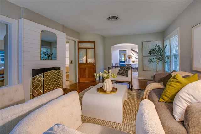 1311 Cedar Hill Ave, Dallas, TX 75208 - living room with arched walkways, wood finished floors, a fireplace, and baseboards