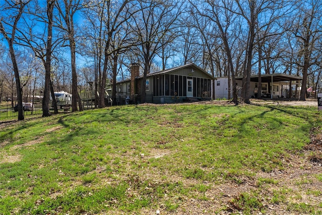 view of yard featuring an attached carport, a sunroom, and fence
