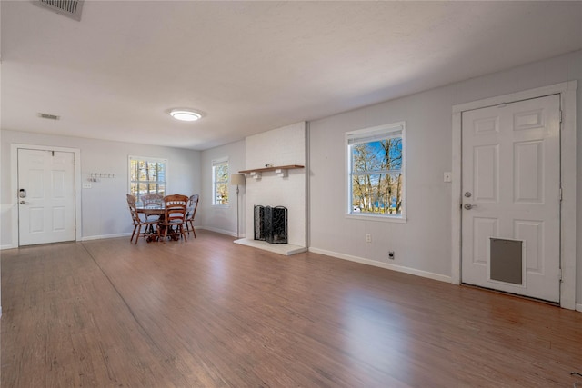unfurnished living room featuring visible vents, baseboards, and wood finished floors