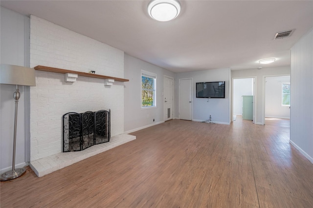 unfurnished living room with visible vents, baseboards, wood finished floors, and a fireplace