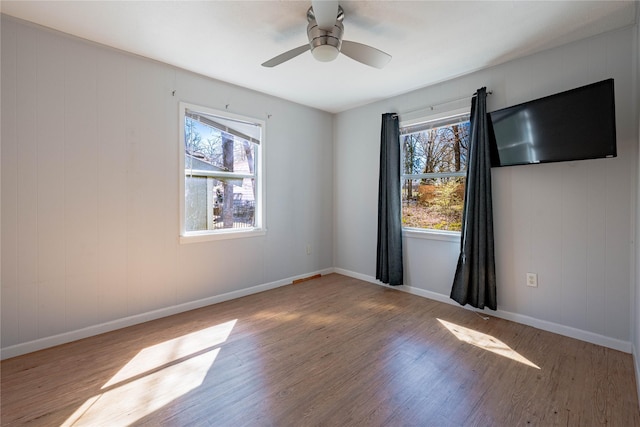 spare room featuring baseboards, wood finished floors, and a ceiling fan