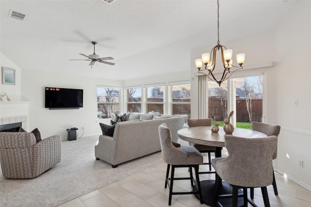 dining area featuring visible vents, ceiling fan with notable chandelier, light colored carpet, and a tile fireplace