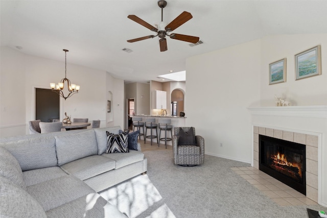 living area featuring light carpet, visible vents, ceiling fan with notable chandelier, and a fireplace