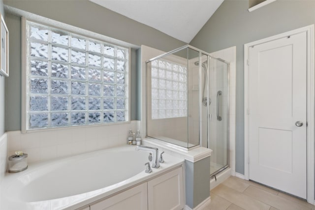 full bath with plenty of natural light, a shower stall, vaulted ceiling, a garden tub, and tile patterned floors