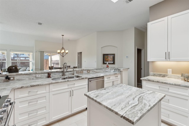 kitchen with light stone counters, stainless steel appliances, a sink, white cabinetry, and a chandelier