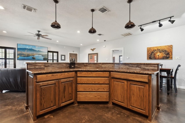 kitchen featuring brown cabinets, finished concrete flooring, visible vents, and a textured ceiling