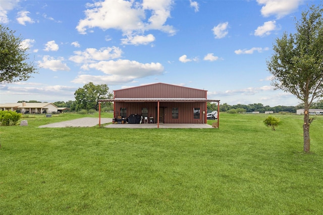 rear view of house with an outdoor structure, a yard, and a pole building