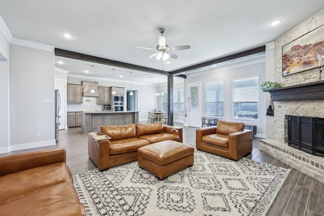 living room featuring baseboards, wood finish floors, beam ceiling, ceiling fan, and a stone fireplace