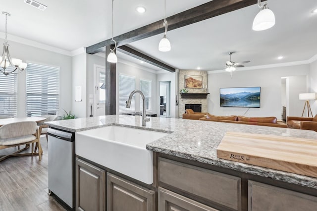 kitchen with visible vents, open floor plan, dishwasher, a stone fireplace, and a sink