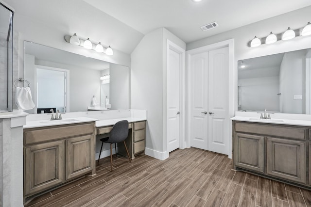 bathroom featuring wood tiled floor, two vanities, visible vents, and a sink