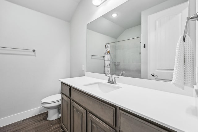 bathroom featuring vanity, wood finished floors, baseboards, a tile shower, and toilet