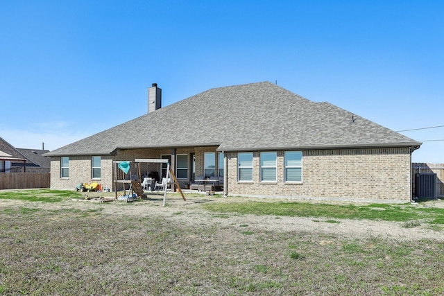 back of house with brick siding, a chimney, and fence