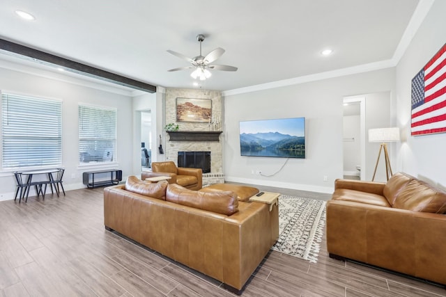 living area with a stone fireplace, wood finish floors, baseboards, and ceiling fan