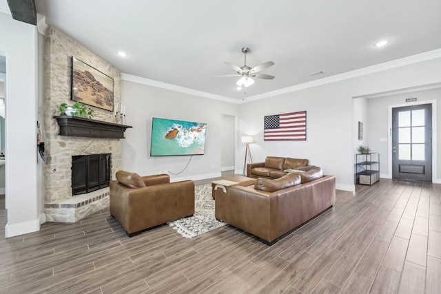 living room with wood finish floors, visible vents, ornamental molding, a stone fireplace, and ceiling fan