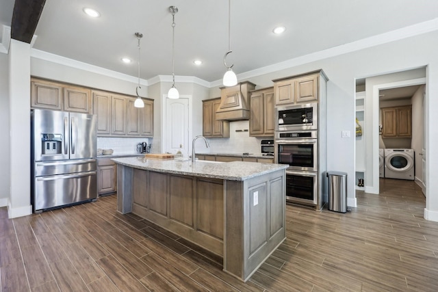 kitchen with light stone counters, wood tiled floor, custom exhaust hood, a sink, and appliances with stainless steel finishes