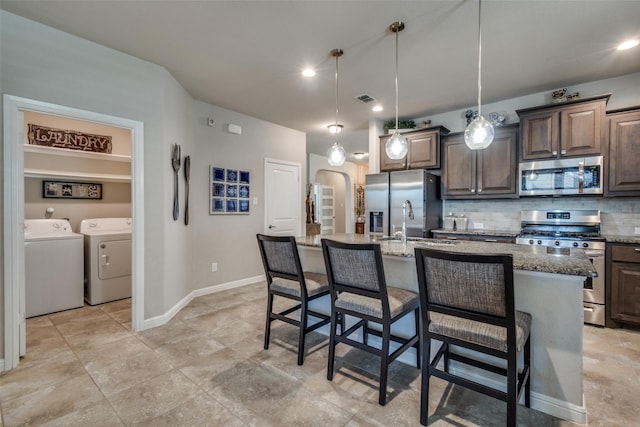 kitchen with visible vents, a breakfast bar, separate washer and dryer, appliances with stainless steel finishes, and backsplash