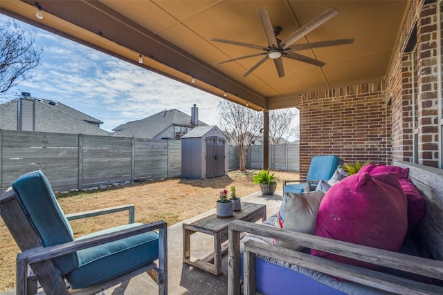 view of patio / terrace featuring an outdoor hangout area, a storage shed, a fenced backyard, an outbuilding, and a ceiling fan