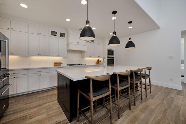 kitchen with stainless steel appliances, tasteful backsplash, light wood-style flooring, and light countertops