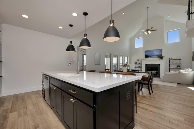 kitchen featuring open floor plan, light wood-style flooring, a fireplace, and a sink