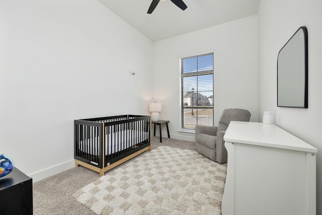 bedroom with a ceiling fan, carpet flooring, baseboards, and a nursery area