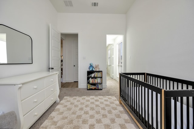 bedroom featuring a nursery area, light colored carpet, visible vents, and baseboards