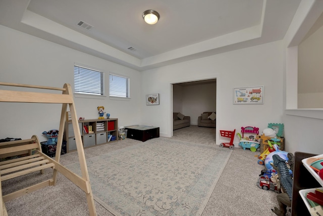 rec room with a tray ceiling and visible vents