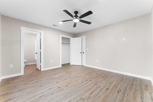 unfurnished bedroom featuring visible vents, baseboards, light wood-style flooring, ensuite bathroom, and a closet