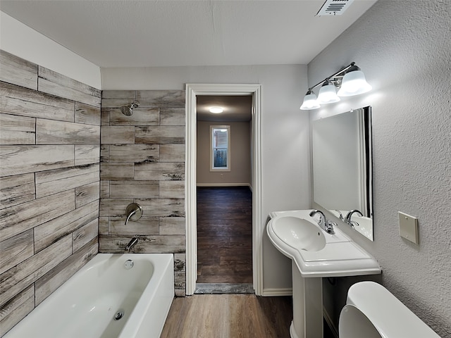 bathroom featuring visible vents, toilet, wood finished floors, bathtub / shower combination, and vanity