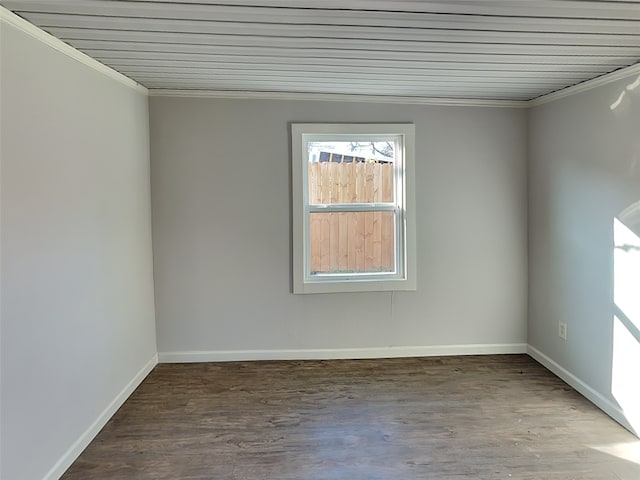 empty room featuring wood finished floors, baseboards, and ornamental molding