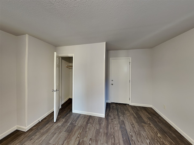 unfurnished bedroom with baseboards, a textured ceiling, and dark wood-style flooring