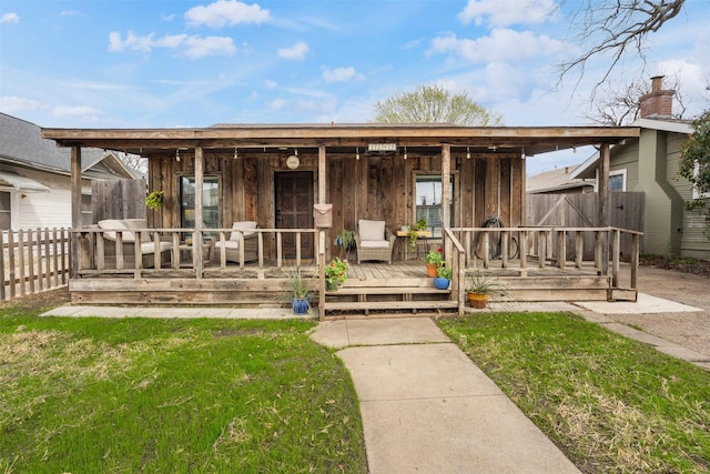 view of front of house with a porch, a front yard, and fence