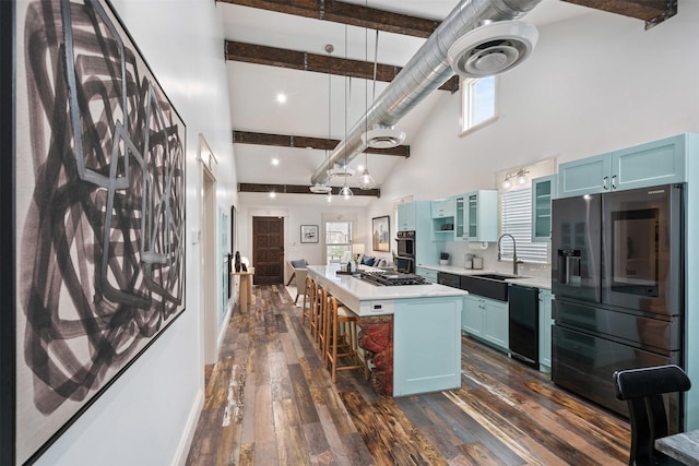 kitchen with a kitchen island, beamed ceiling, stainless steel fridge, blue cabinets, and a sink