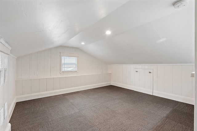 bonus room featuring lofted ceiling and dark colored carpet