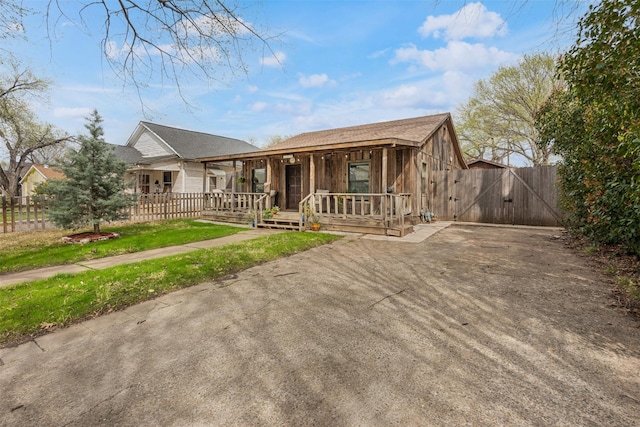 view of front of house featuring fence, a porch, driveway, and a gate