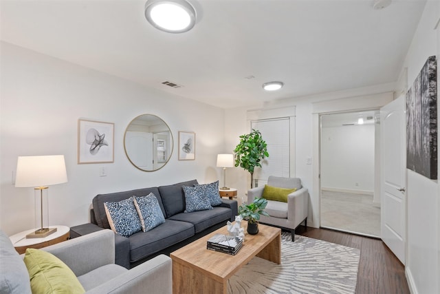 living room with visible vents, baseboards, and dark wood-style flooring