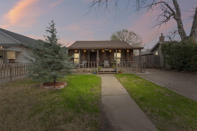 bungalow-style home with a front lawn, fence, and covered porch