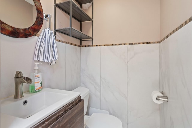 bathroom with vanity, tile walls, and toilet