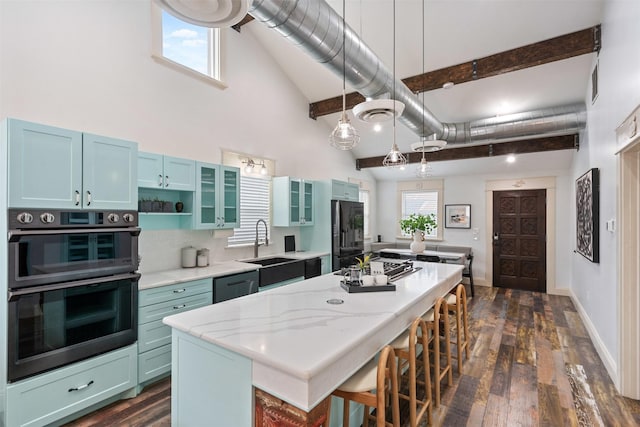 kitchen featuring dark wood-type flooring, a kitchen island, freestanding refrigerator, a breakfast bar area, and a towering ceiling